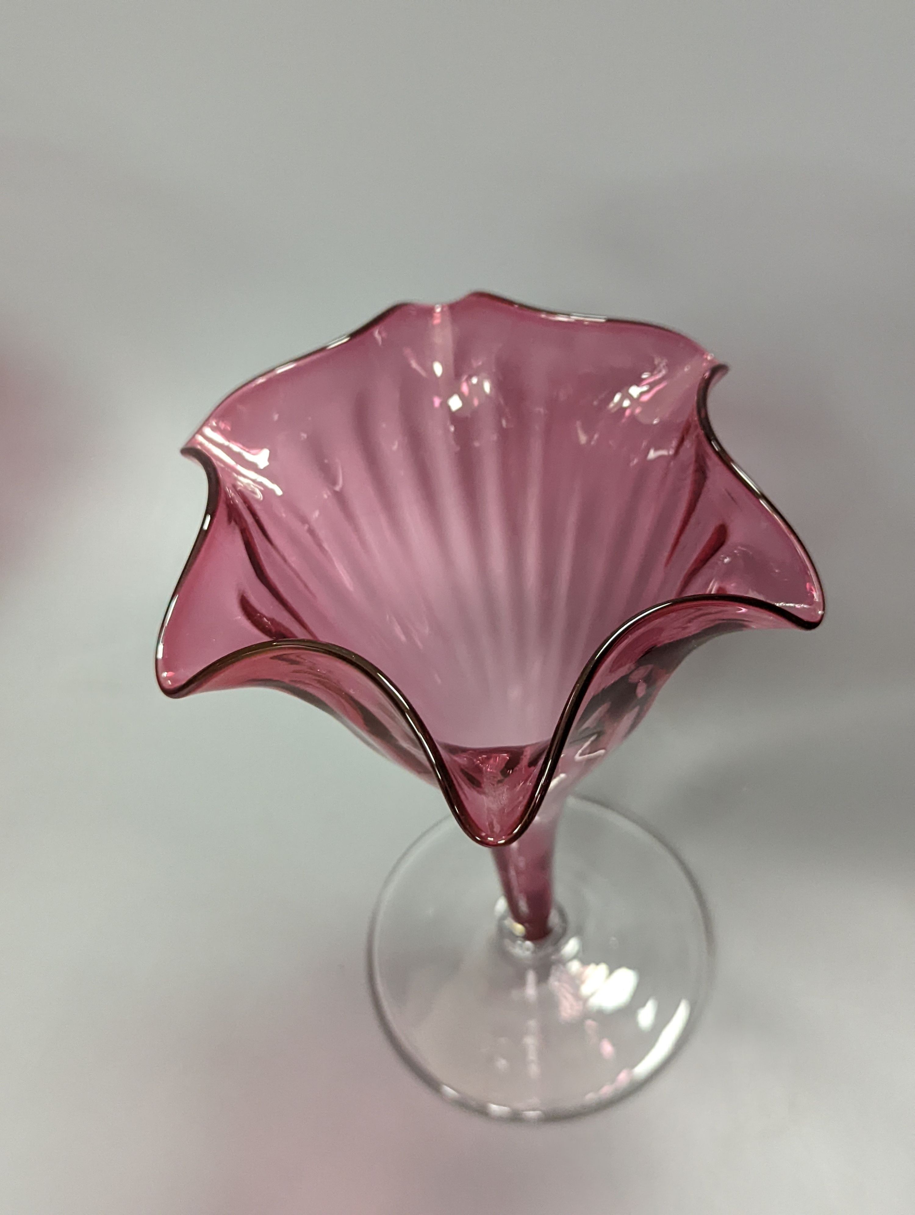 A pair of late Victorian cranberry glass frill vases, height 23cm, and a similar tapering jug